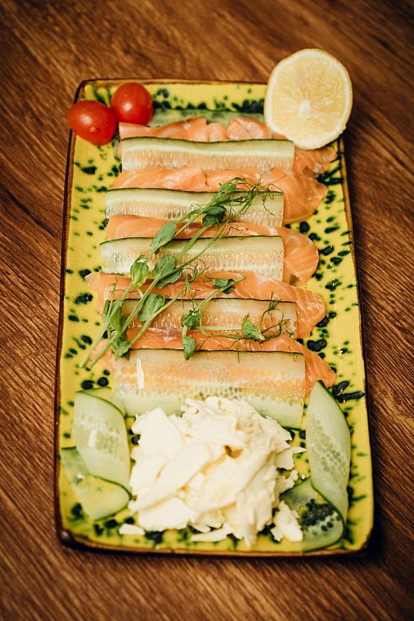 Слайсы слабосоленого лосося, тосты, сливочным маслом и свежим огурцом